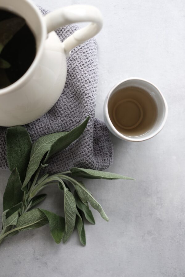 Sage leaves and white teapot and mug. How to sooth a sore throat - you can use sage tea. Recipe from the Make Your Own Immunity Herbal Remedy Kit | Everyday Empowered