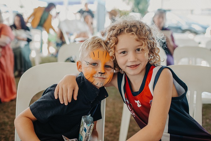 Herbest 2023 - happy kids, grassroots herbal medicine community event and gathering. Image of two boys smiling, one with his face painted like a tiger.