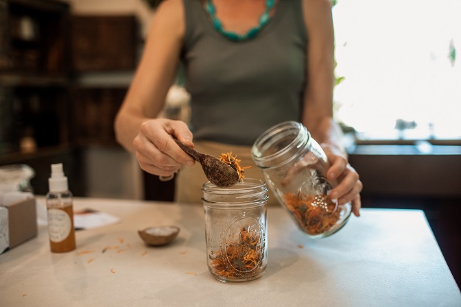 Putting calendula in jar to remedy from the Herbal Starter Kit. Learning to make simple herbal medicine to use in daily life.