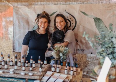 Image of HerbFest herbal stall with women smiling and herbal products in the foreground. HerbFest is the Sunshine Coast's annual herbal medicine community event. Everyday Empowered