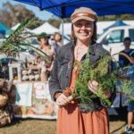 Image of woman smiling holding plants at HerbFest. HerbFest is the Sunshine Coast's annual herbal medicine community event. Everyday Empowered