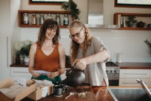 Building immunity and winter wellness with herbal remedies. Image of Cat Green and Heidi Merika pouring tea and making herbal remedies to support immunity in the kitchen